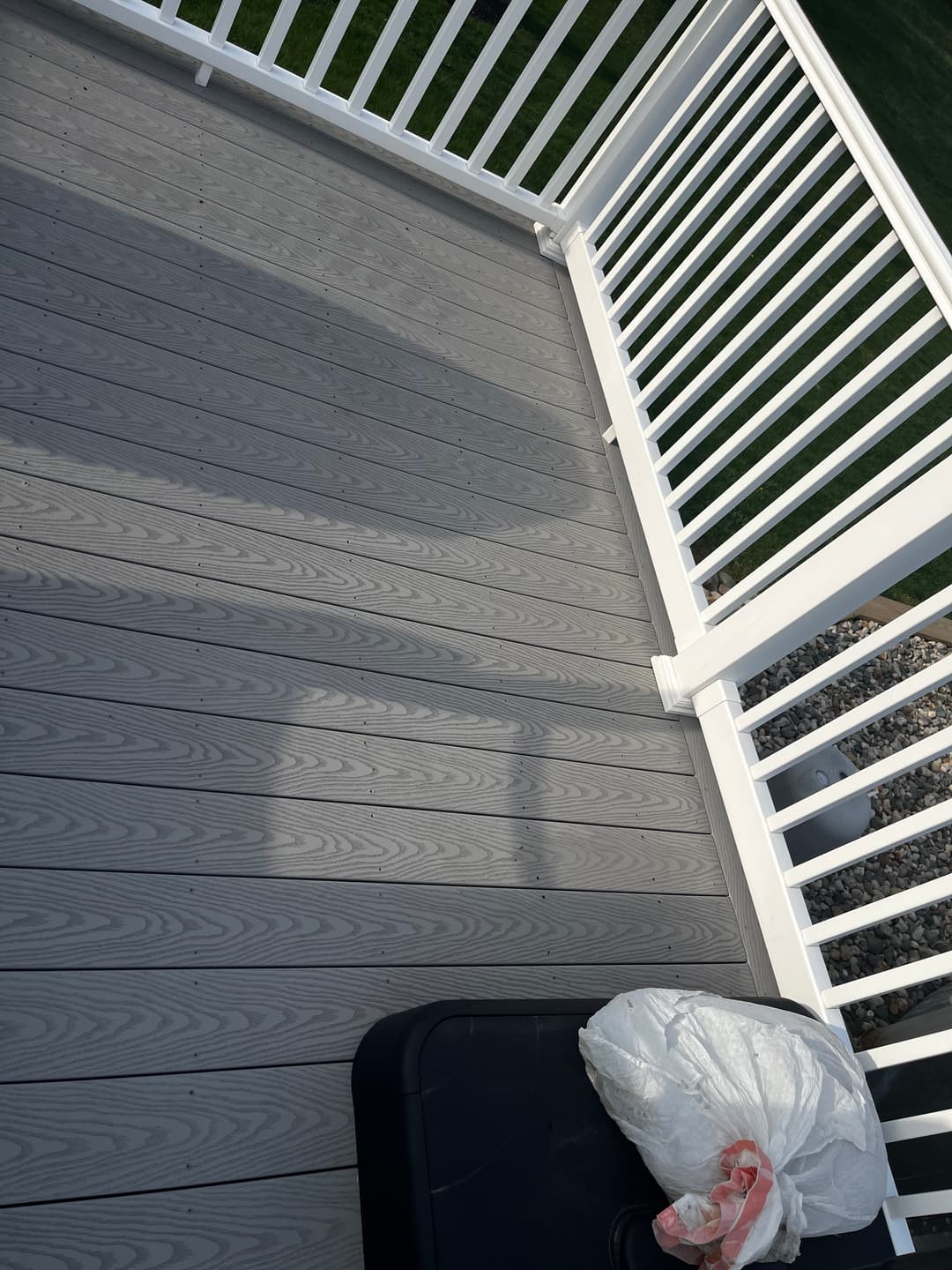 Modern grey deck with white railing and a black storage box on the side.