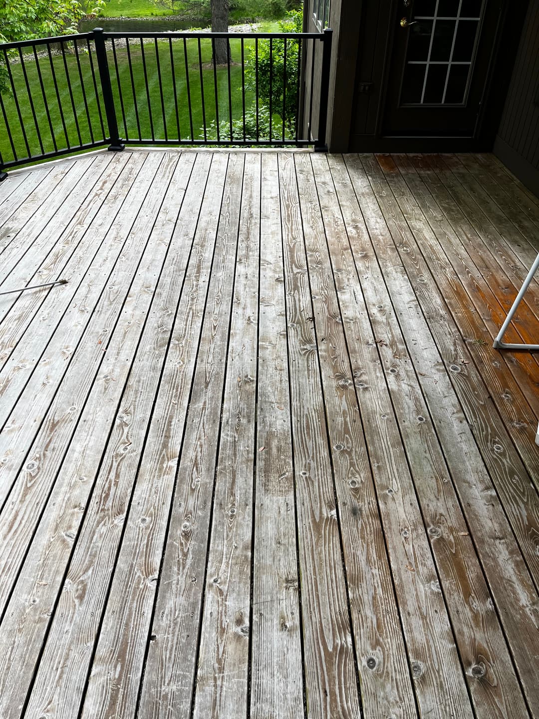 Weathered wooden deck with natural wood grain and green grass in the background.