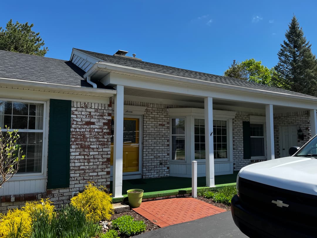 Charming brick home with yellow door, landscaped yard, and clear blue sky above.