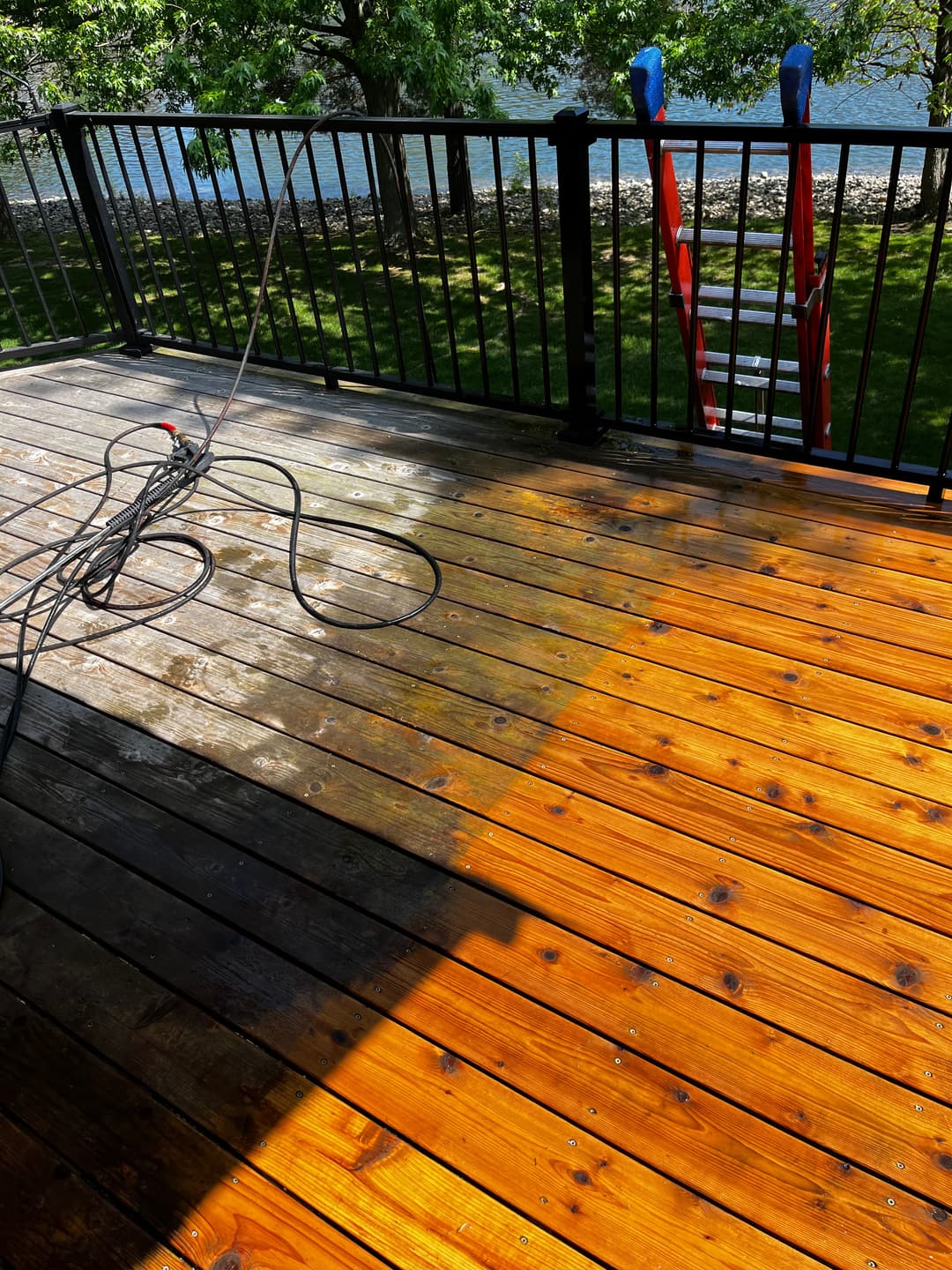Before and after cleaning wood deck, showing contrast between stained and clean areas.