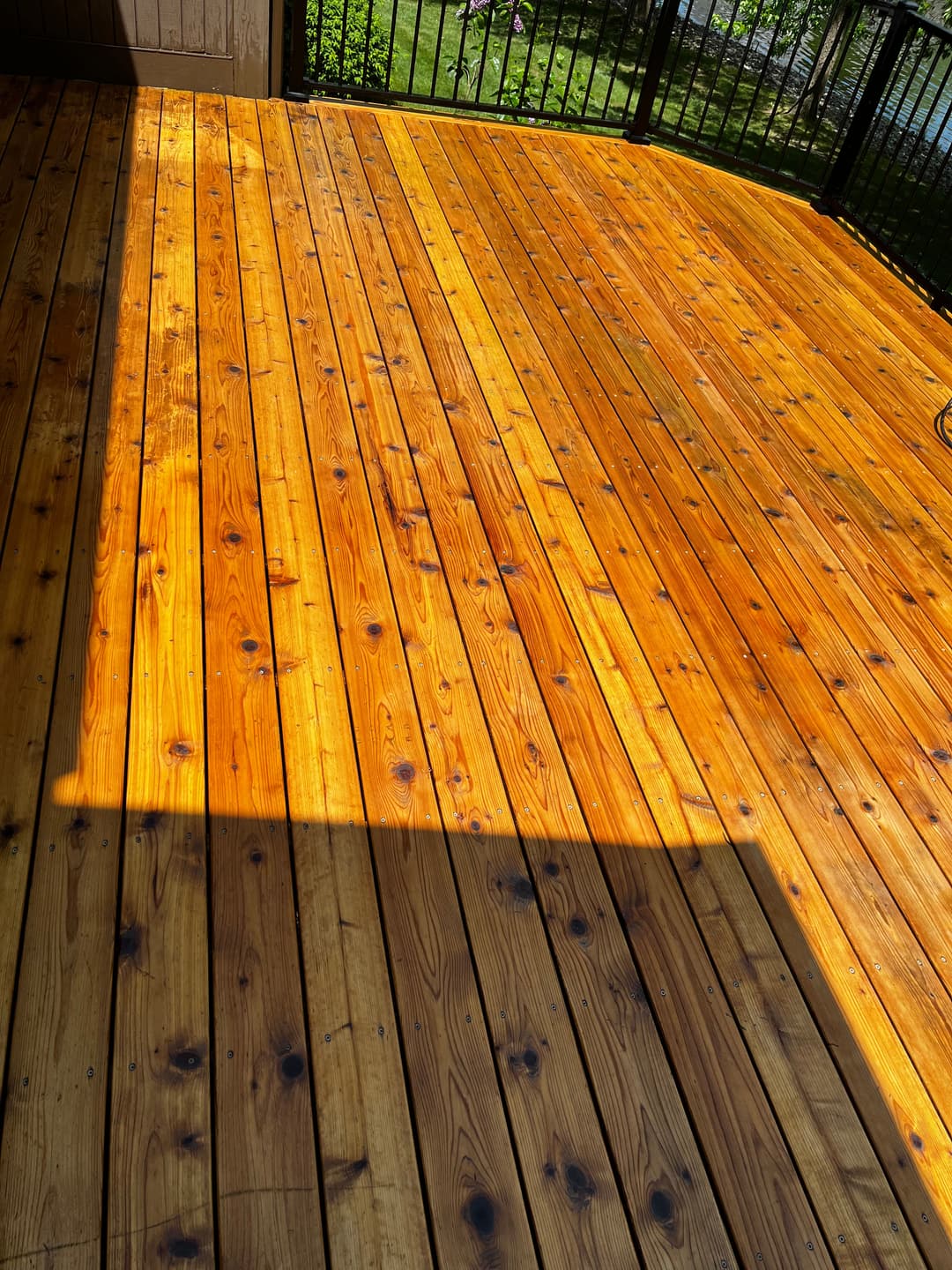 Clean, polished wooden deck with natural grain patterns and warm sunlight highlights.