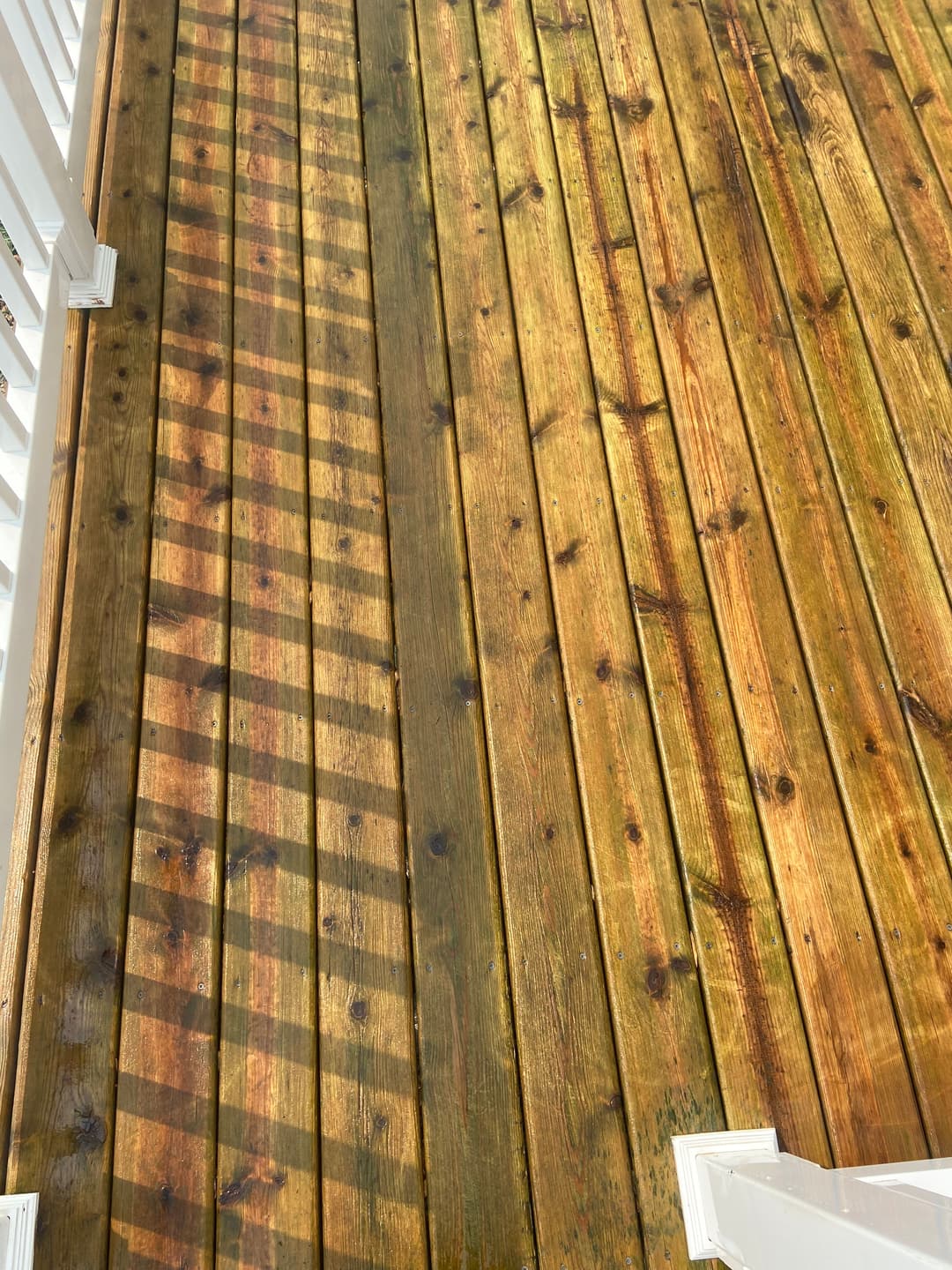 Well-maintained wooden deck with sunlight casting shadows from railing.