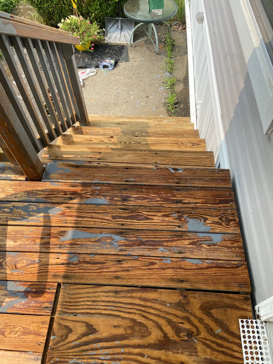 Weathered wooden stairs with peeling paint and a grassy edge, showcasing home maintenance.