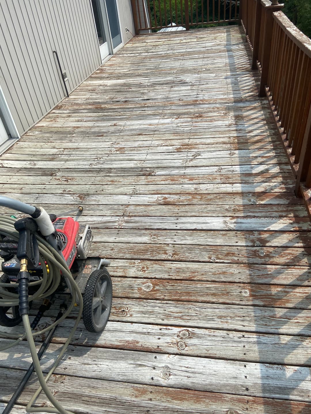 Weathered wooden deck with pressure washer parked nearby, showcasing maintenance potential.