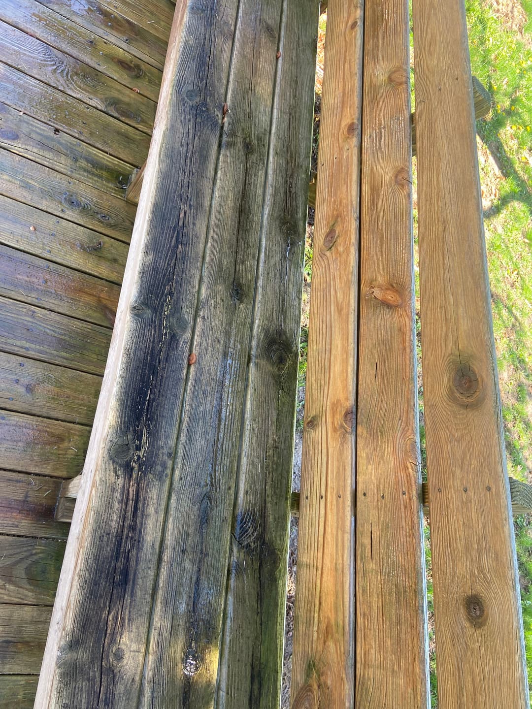 Wooden deck showing contrast between cleaned and uncleaned planks, highlighting restoration work.