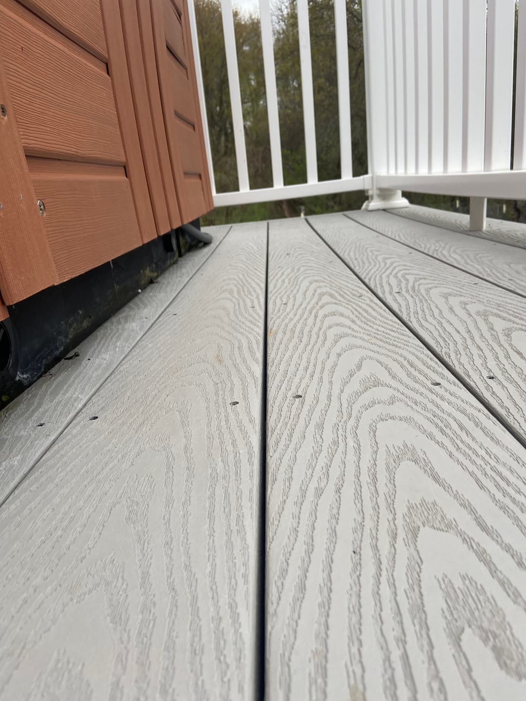 Gray wood decking with a close-up view, featuring natural grain patterns and adjacent railing.