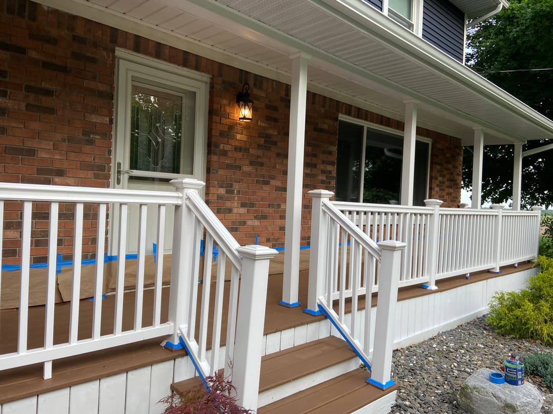 Home entrance with freshly painted brown wooden steps and white railings, ready for finishing touches.