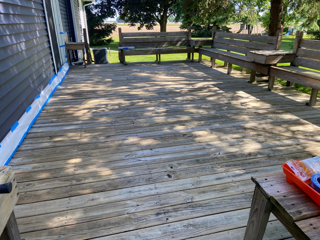 Wooden deck renovation in a backyard, showcasing clean planks and surrounding greenery.