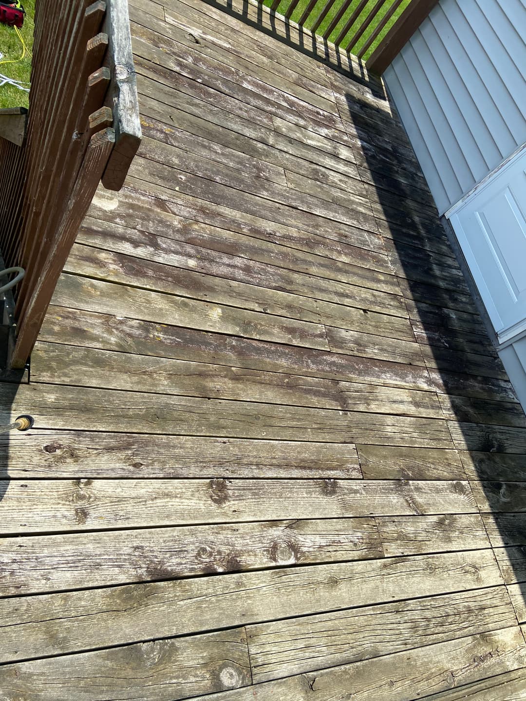 weathered wooden deck with shadows from nearby railing and wall