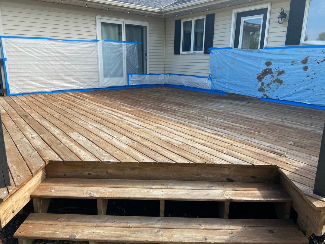 Wooden deck with blue protective covering, ready for renovation. Steps leading into the house.