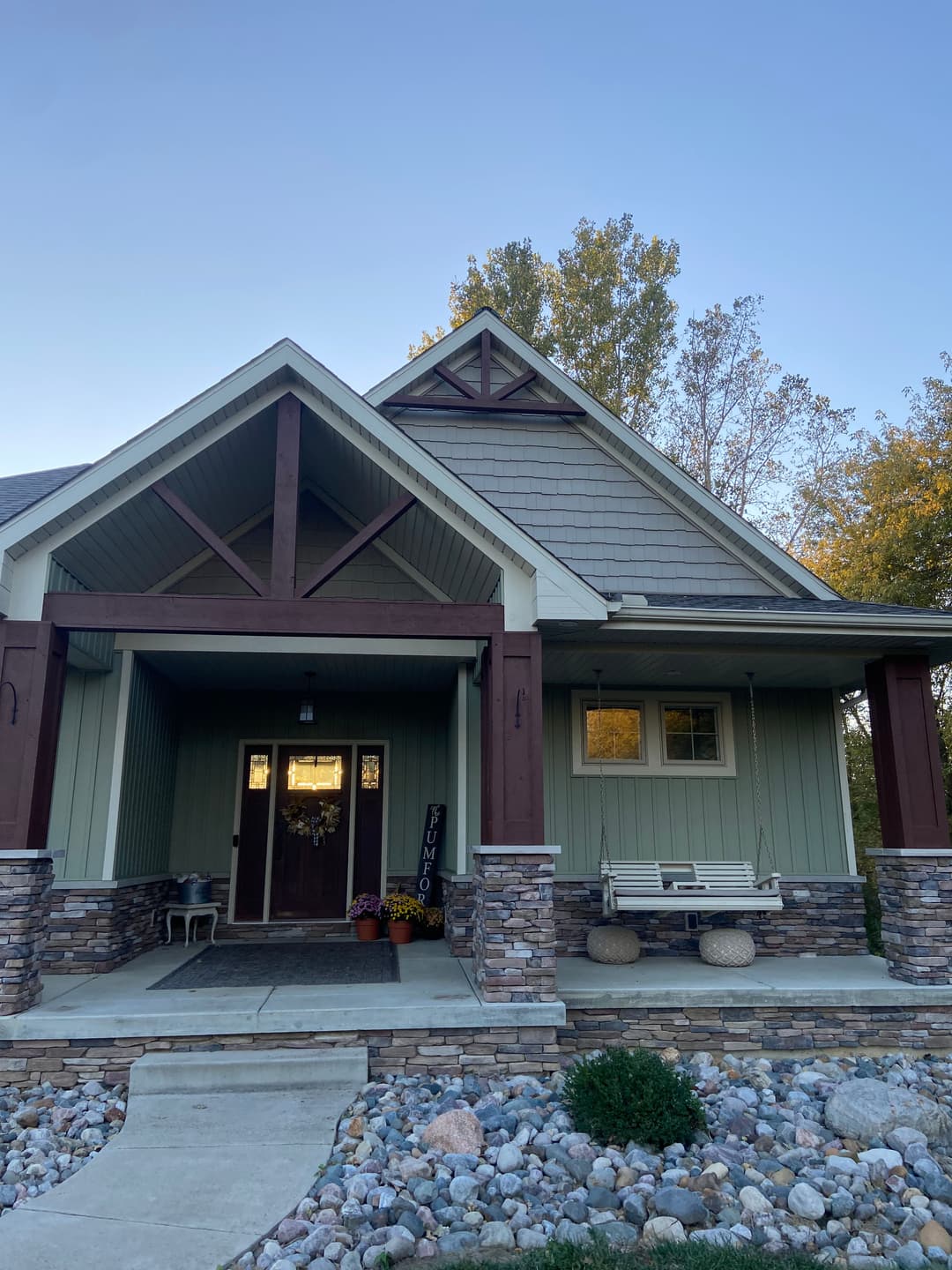 Front view of a modern home with stone accents, porch swing, and landscaped yard.
