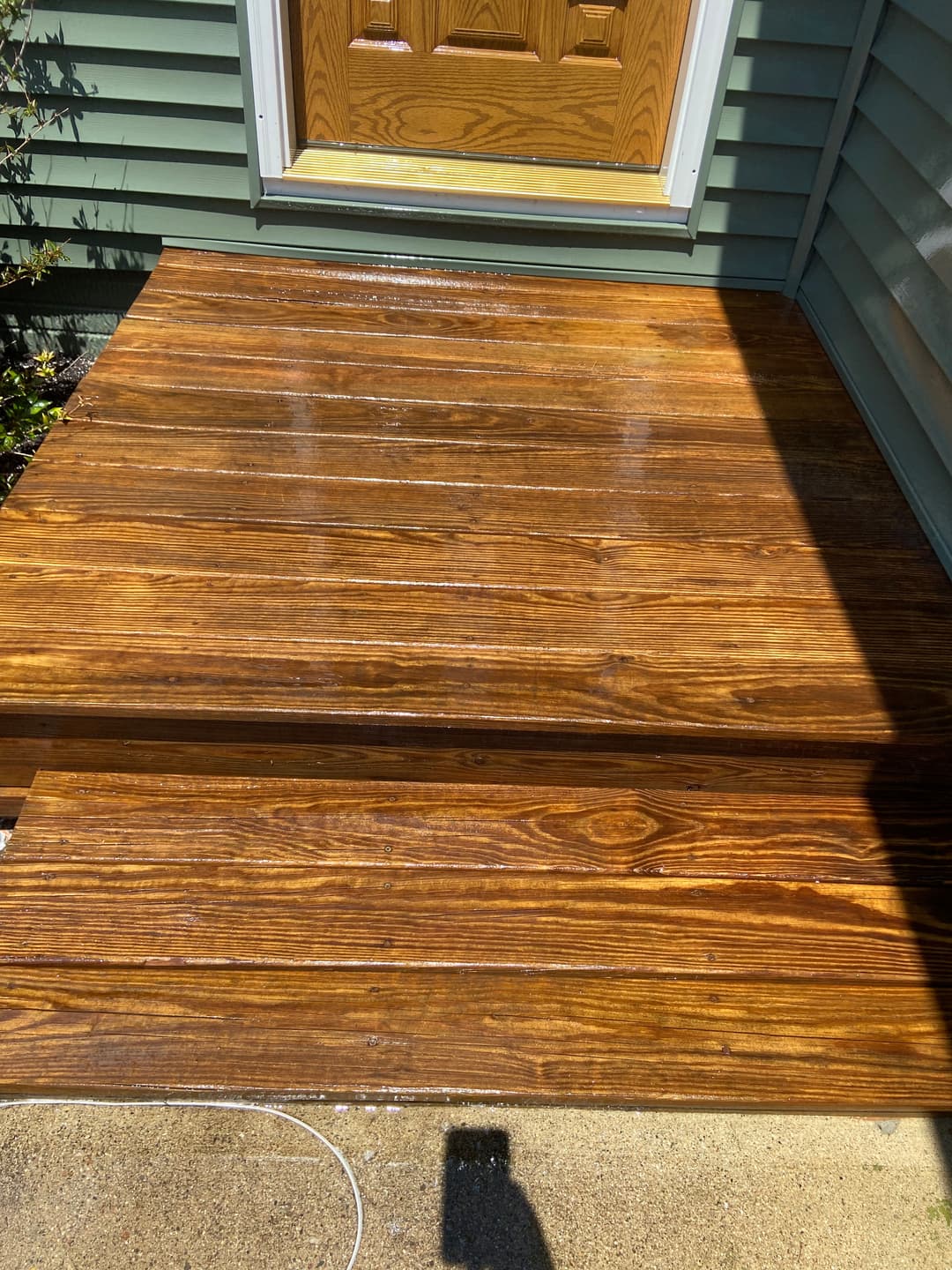 Shiny wooden porch with freshly applied stain and a welcoming front door.