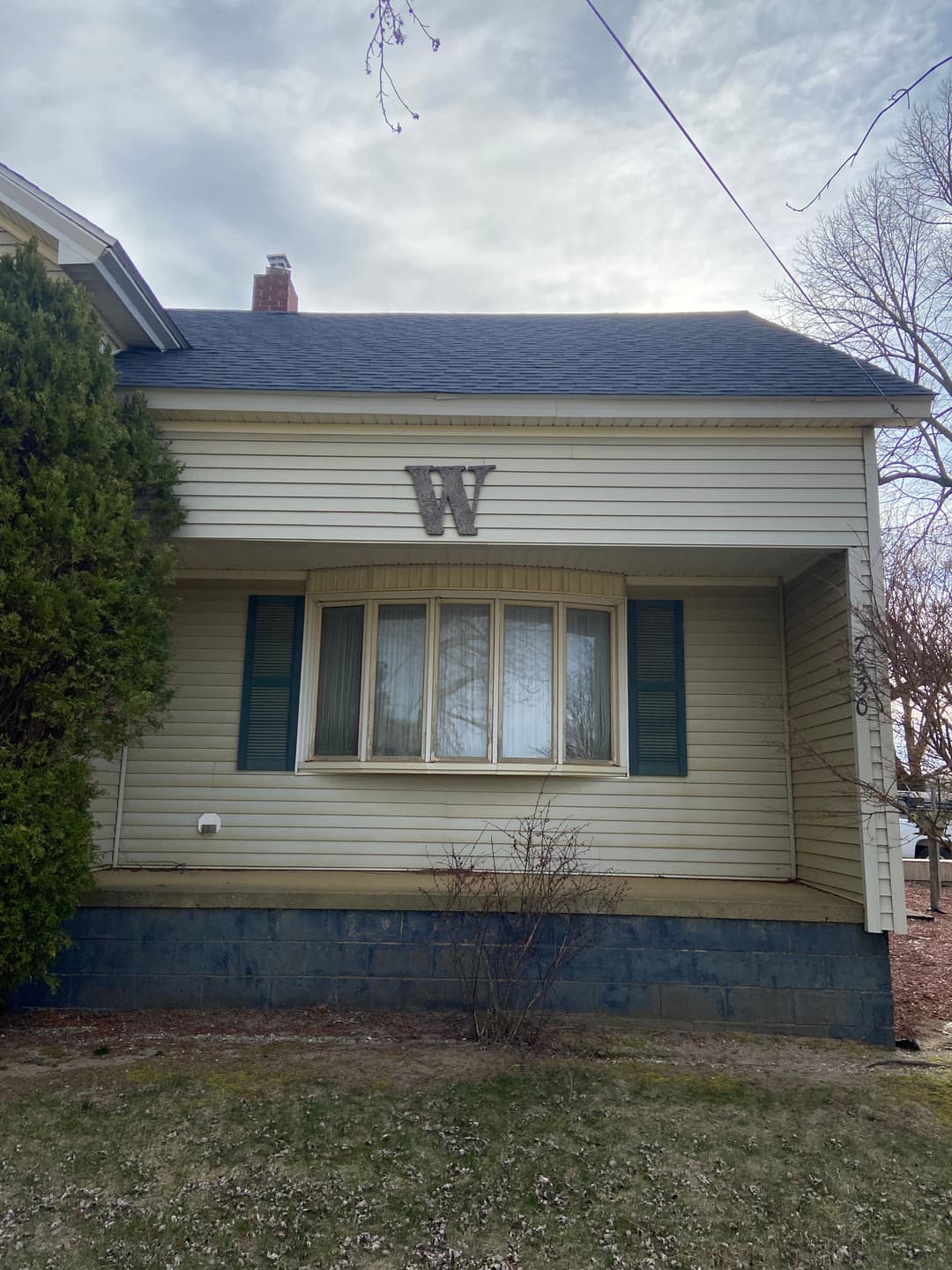 Front view of a house with green shutters and a large letter 'W' above the window.