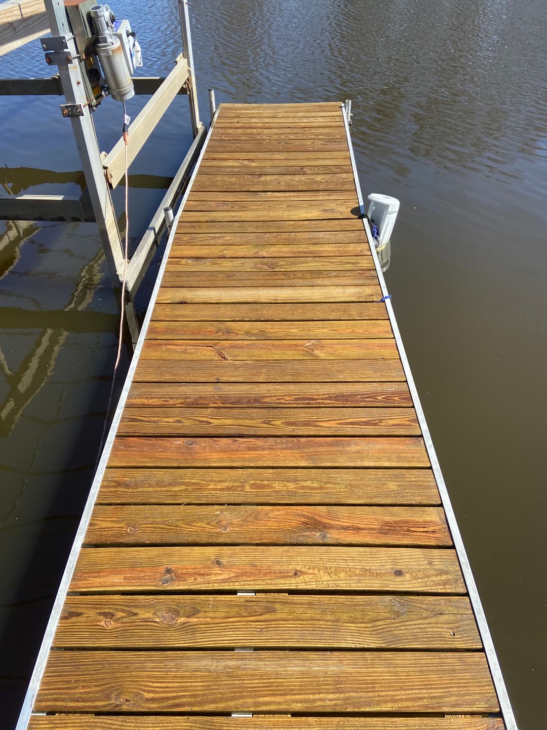 Wooden dock leading to calm water, showcasing a peaceful waterfront setting.