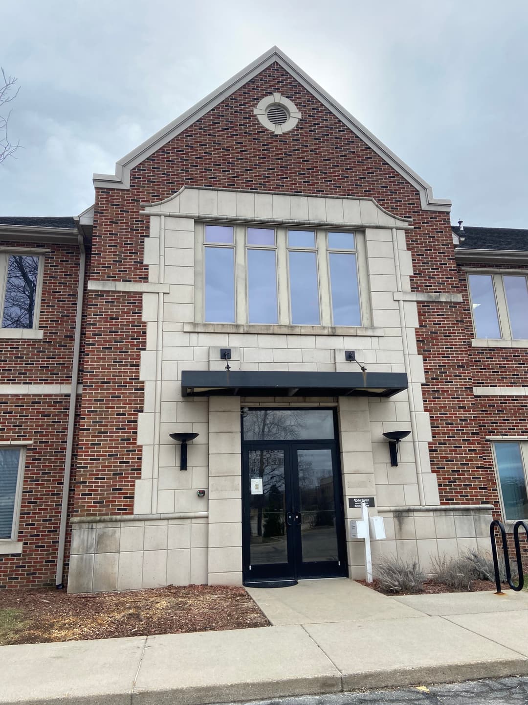 Brick building entrance with large windows and a prominent peaked roof design.