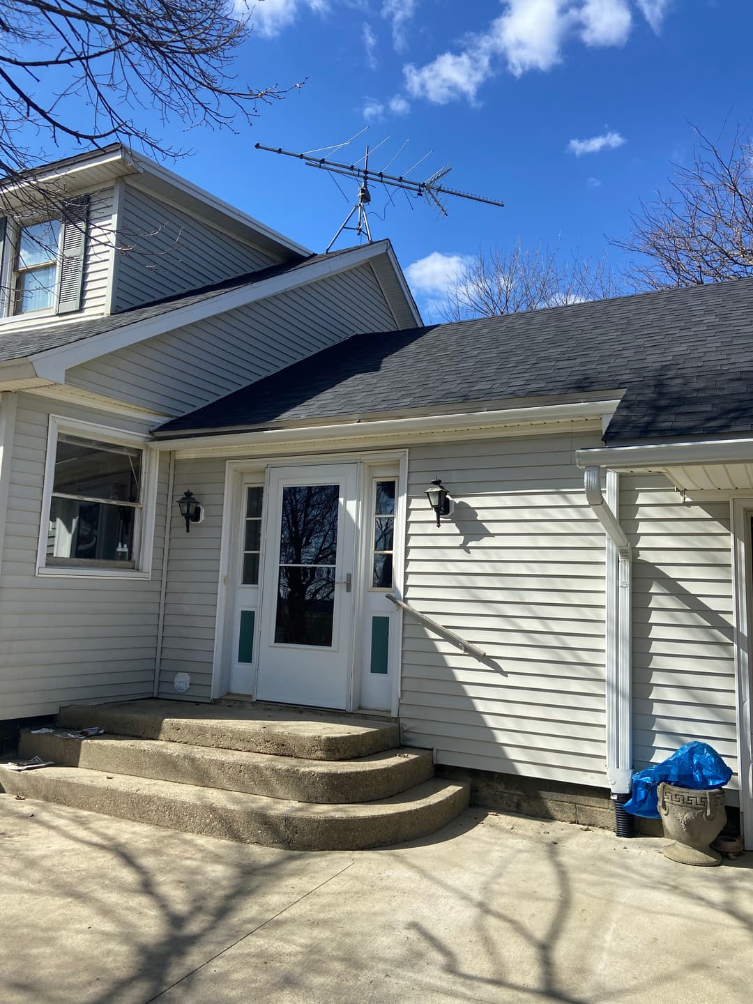 Exterior view of a house with a satellite antenna, steps, and a clear blue sky.