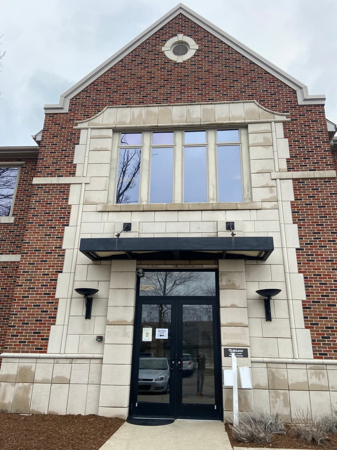 Brick building entrance with large windows and black double doors, modern architectural design.