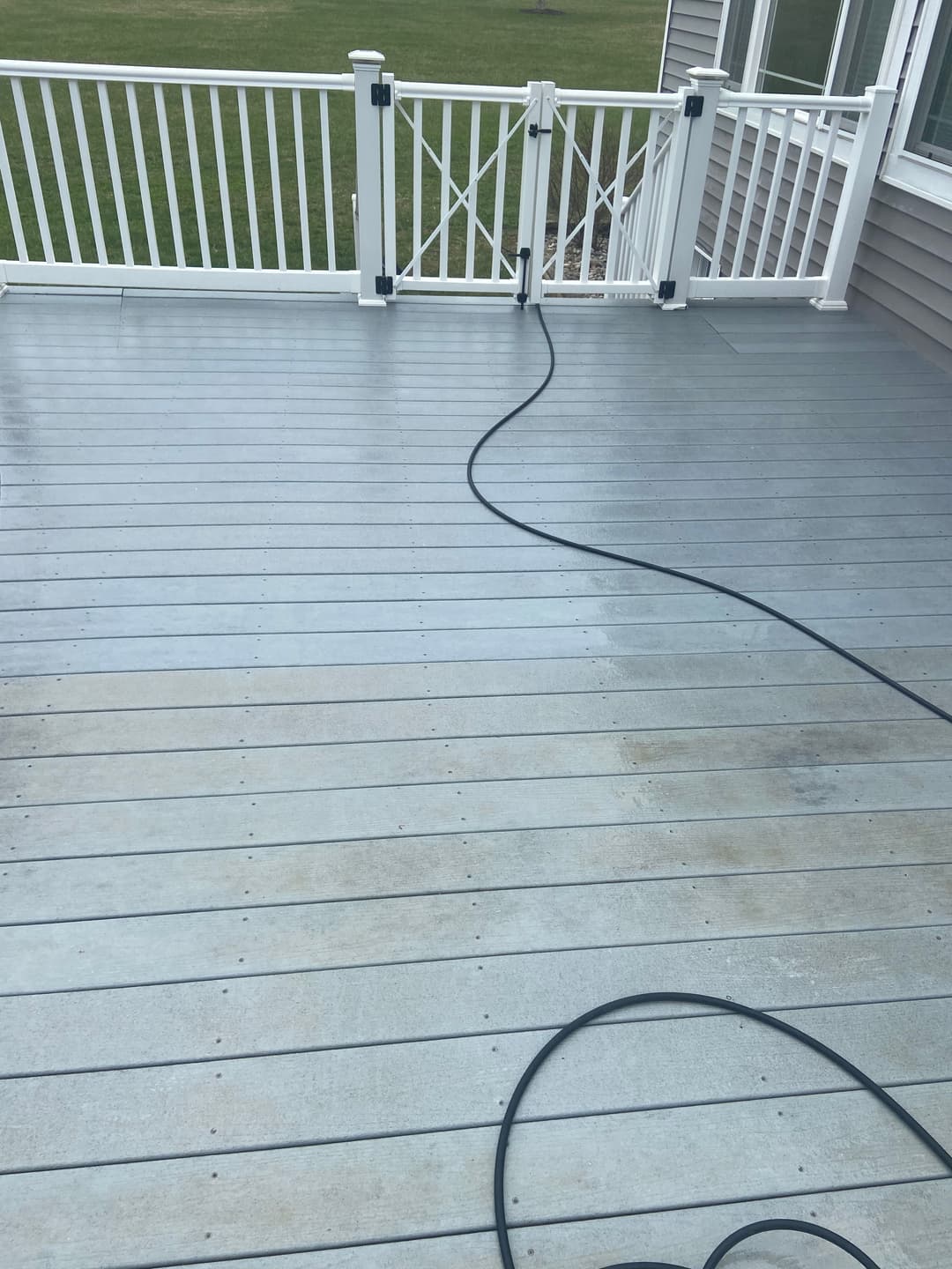 Clean gray deck with white railings and a hose draped across the surface.