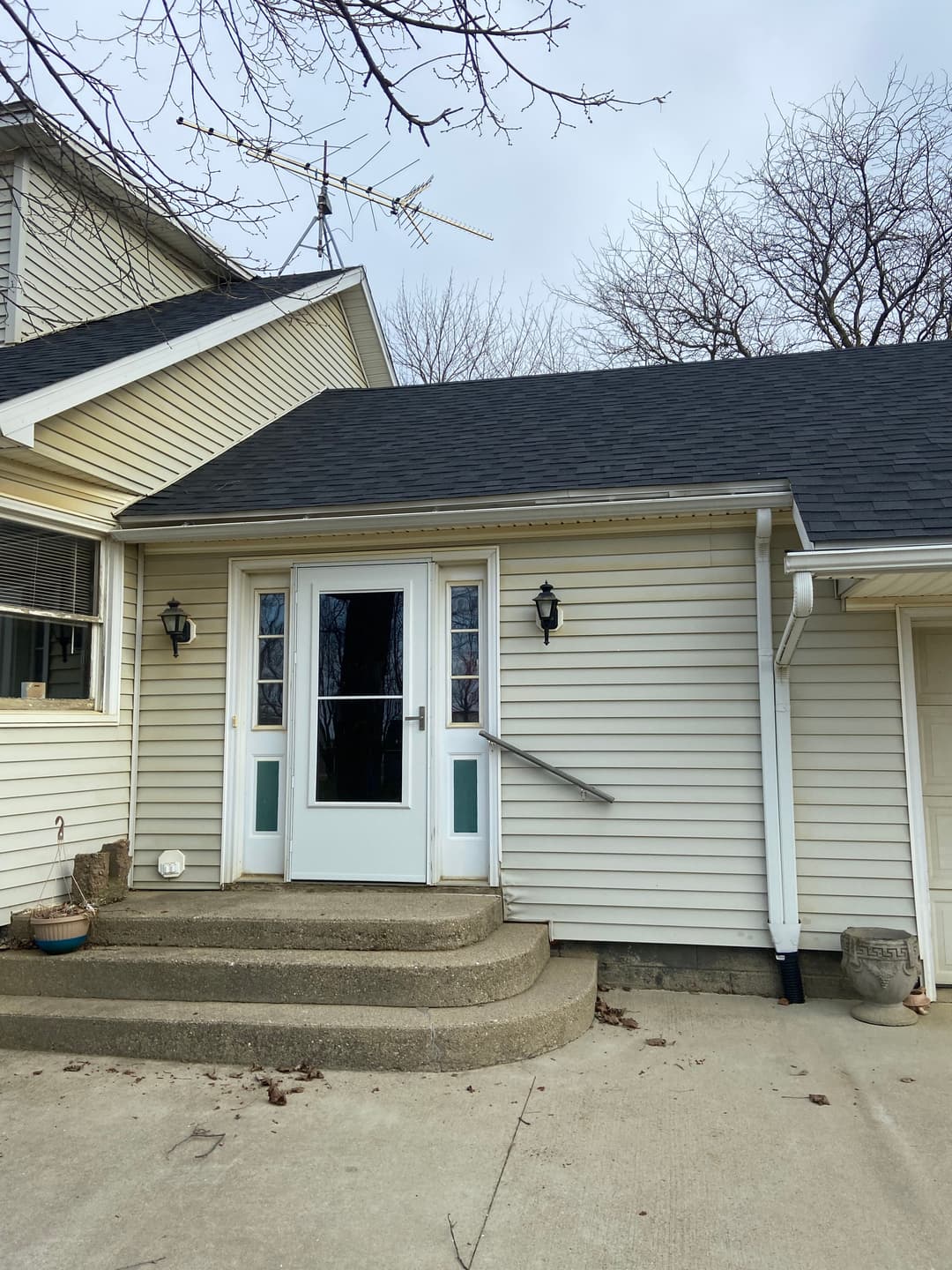 Front entrance of a residential house with steps and a porch, featuring a double door and light fixtures.