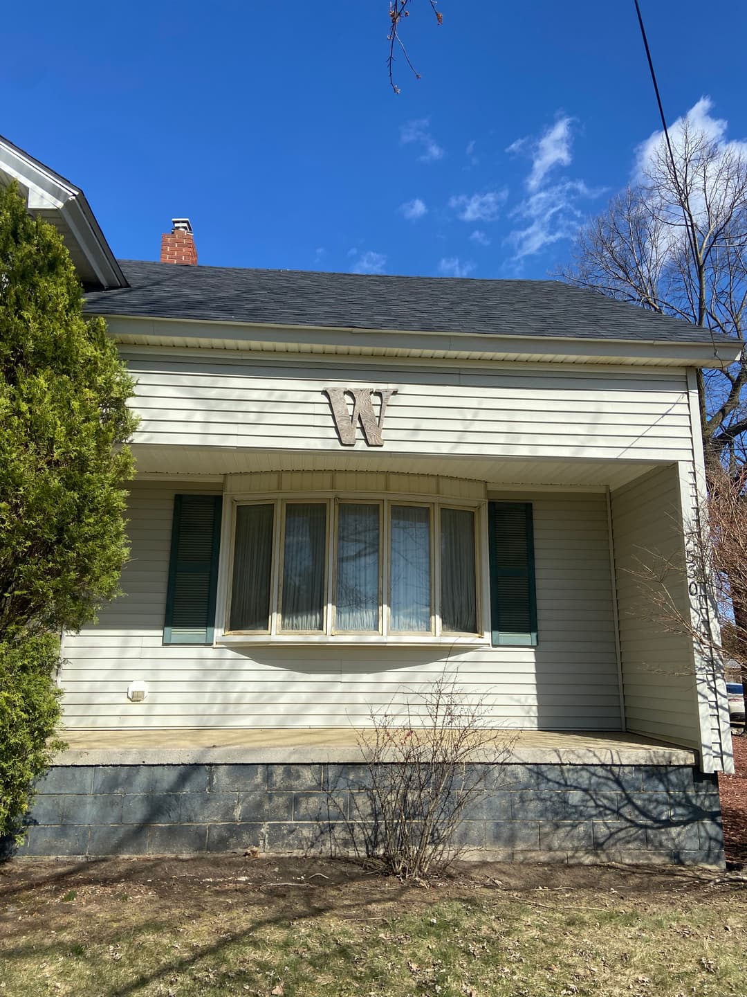 Front view of a single-story home featuring a prominent "W" emblem and green shutters.