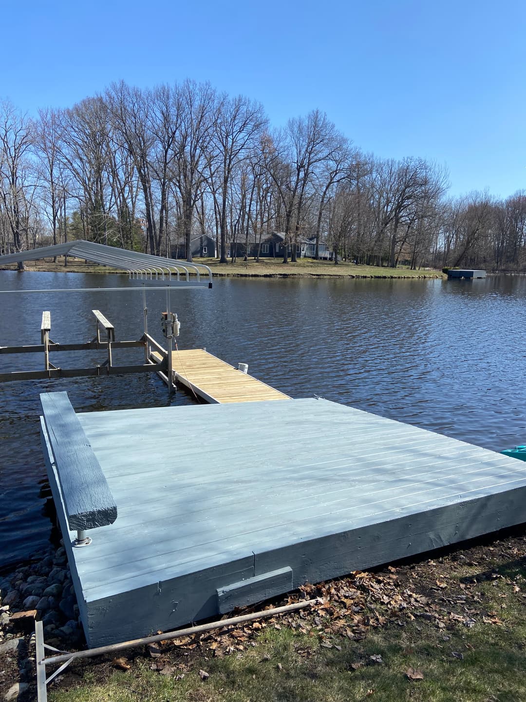 Scenic lake view with a wooden dock and platform surrounded by trees on a sunny day.